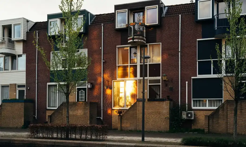 Nederlandse rijtjeswoning bij avond met één verlicht raam